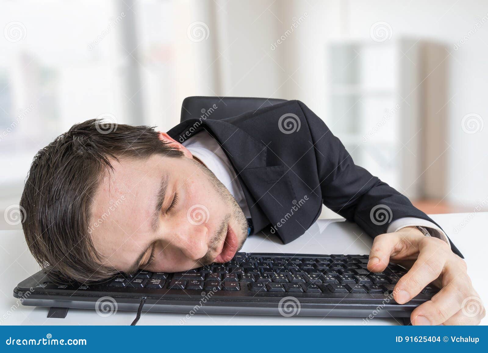 exhausted or tired businessman is sleeping on keyboard in office