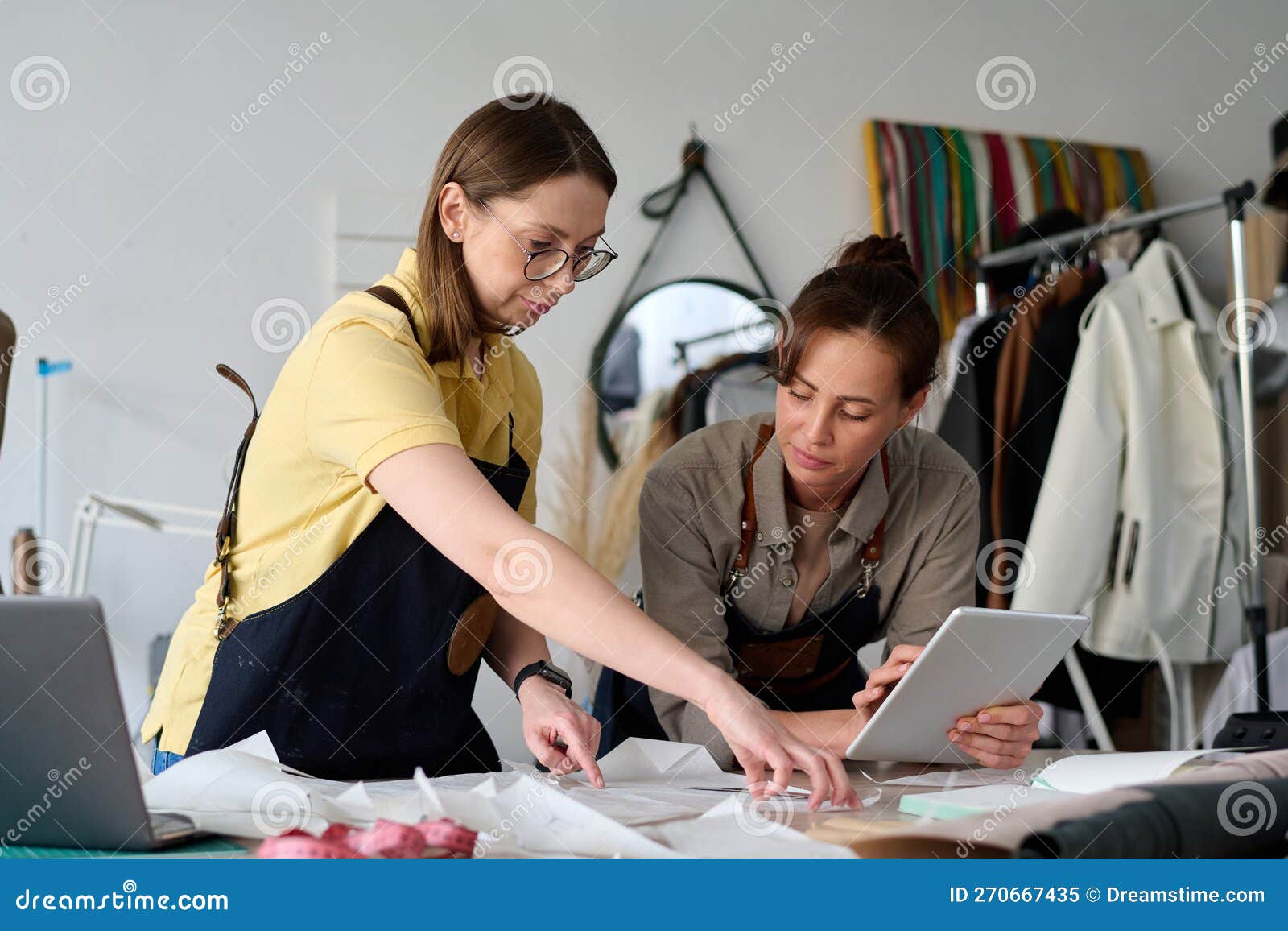 Experienced Tailor and Her Young Assistant Looking at Sewing Pattern