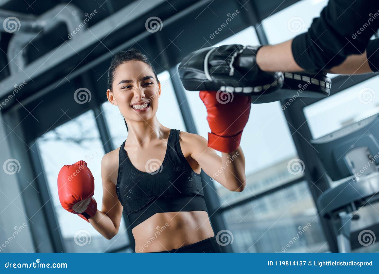 expressive young female boxer exercising with trainer