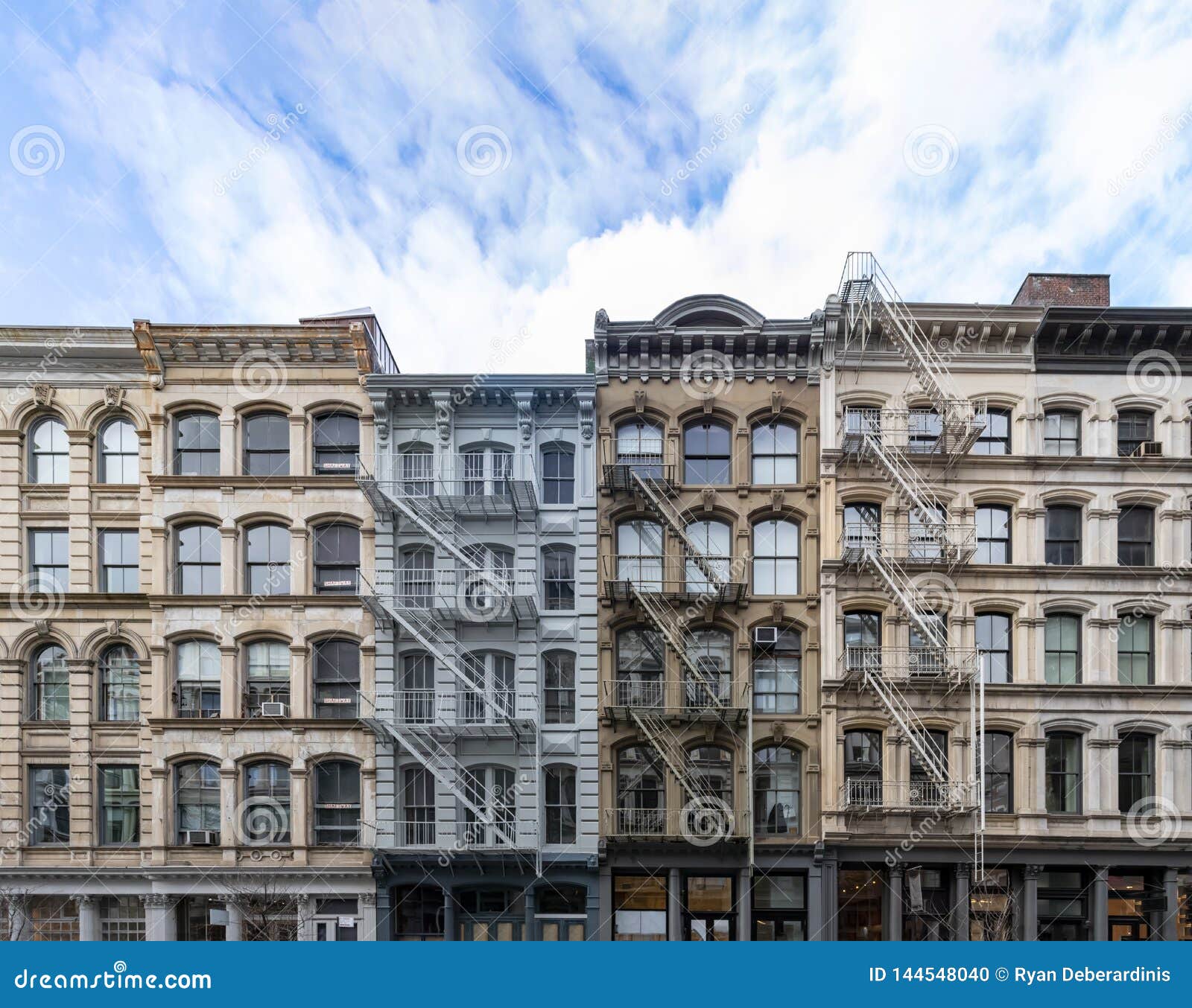 exterior view of old apartment buildings in the soho neighborhood of manhattan in new york city with empty blue sky