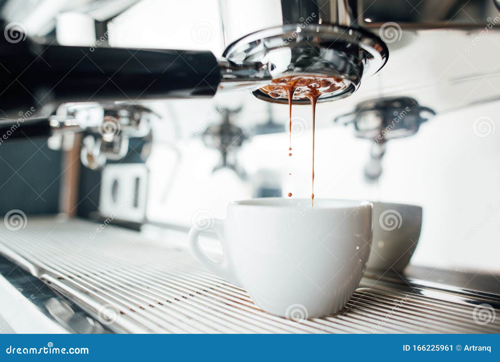 extraction of espresso from bottomless portafilter in white cup