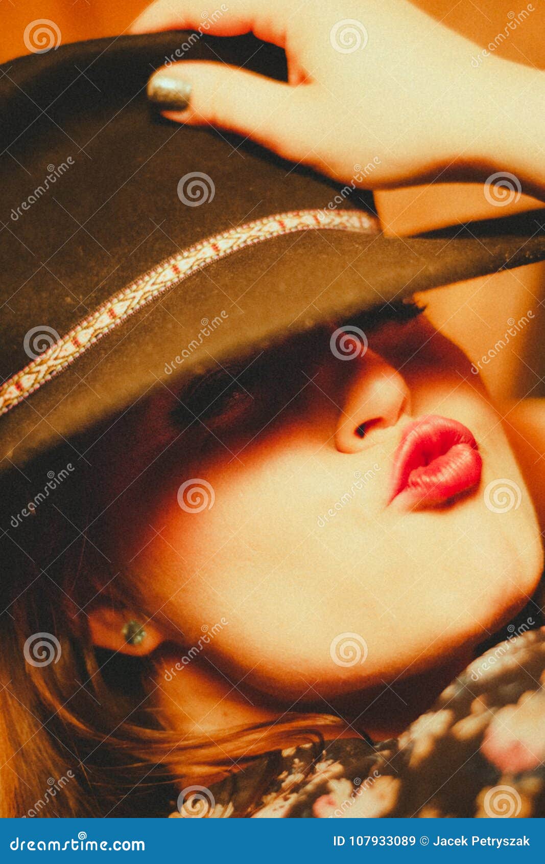 Extrem kissable Lippen. Schönheit umfasst ihren Kopf mit schwarzem Hut und sendet einen reizenden Kuss