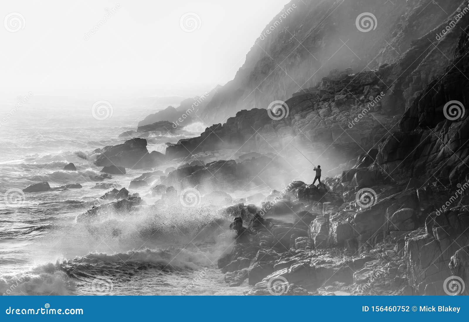 extreme crazy fishing in stormy conditions at porth nanven in cornwall. waves and sea spray backlit by sun