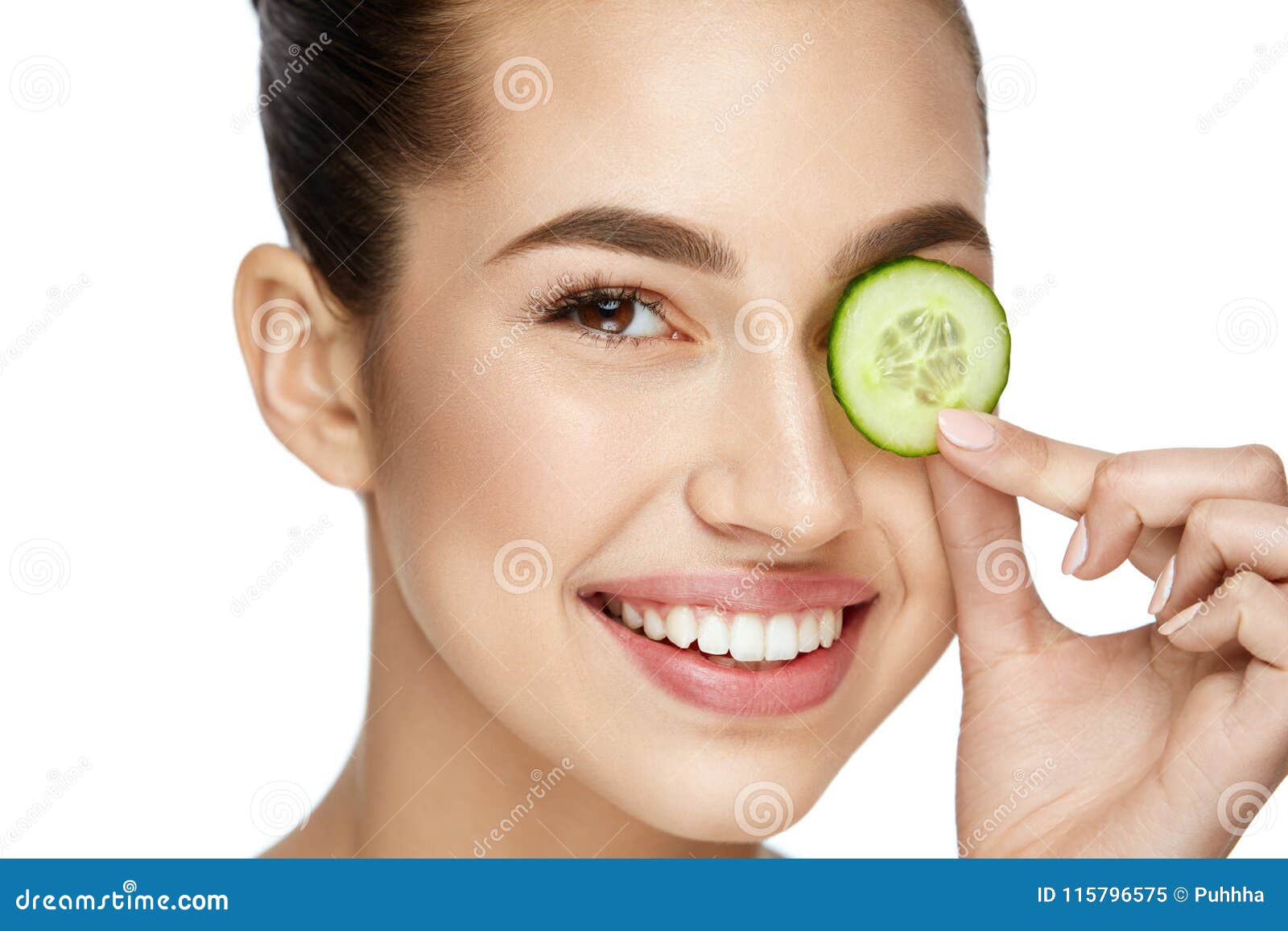 eye skin care. woman with natural makeup using cucumber