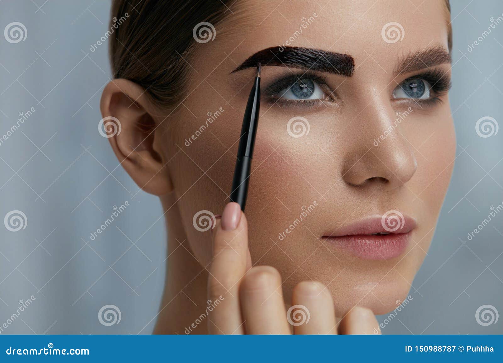 eyebrow coloring. woman applying brow tint with makeup brush