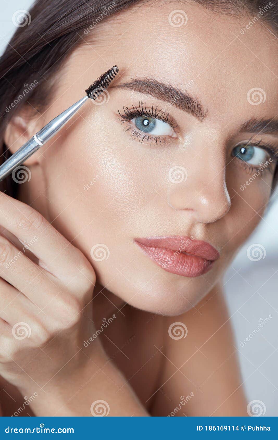 eyebrow makeup. woman brushing brows with brush. beautiful girl with blue eyes and perfect skin