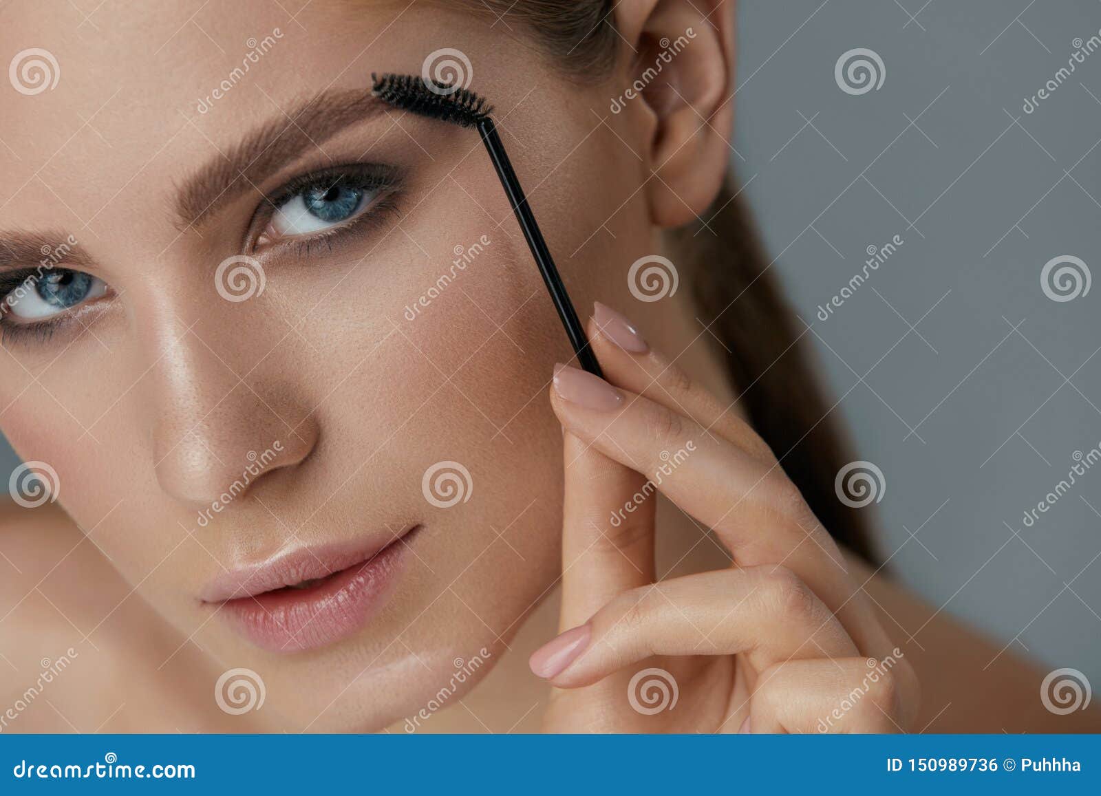 eyebrow makeup. woman brushing brows with gel brush closeup