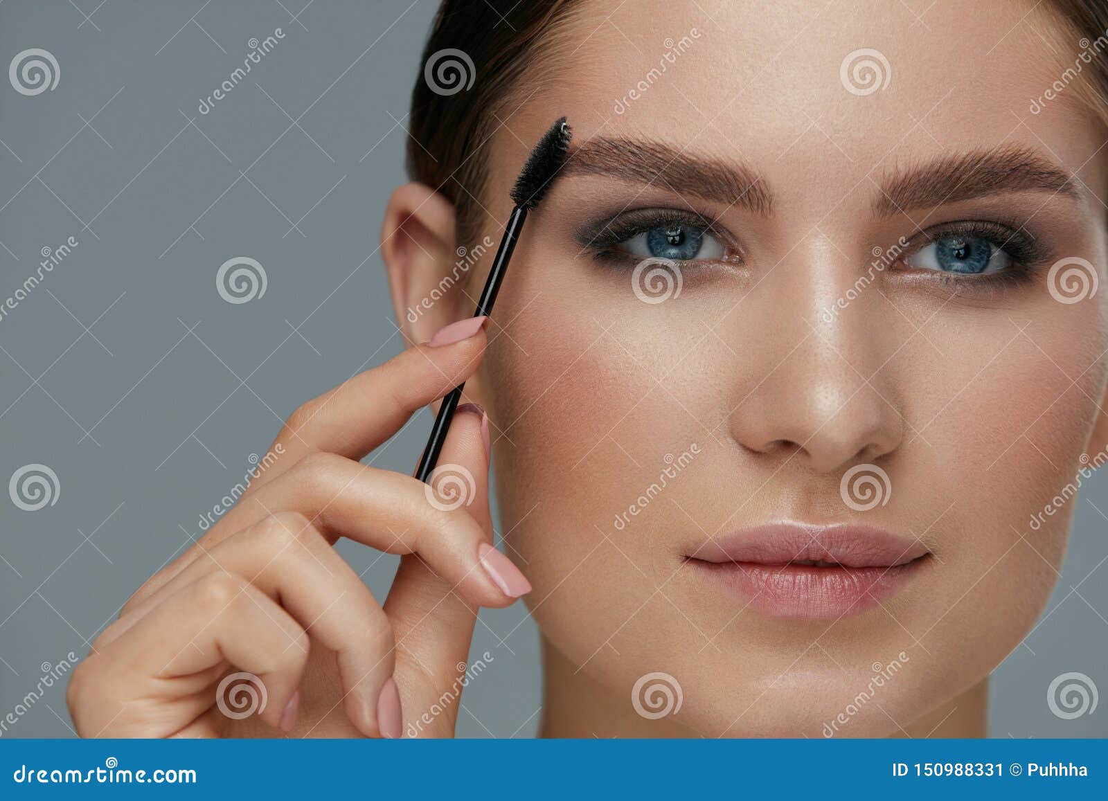 eyebrow makeup. woman brushing brows with gel brush closeup