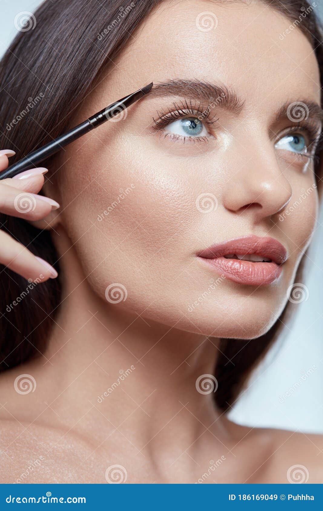 eyebrows makeup. woman shaping brow with cosmetic brush. beautiful girl close up portrait.