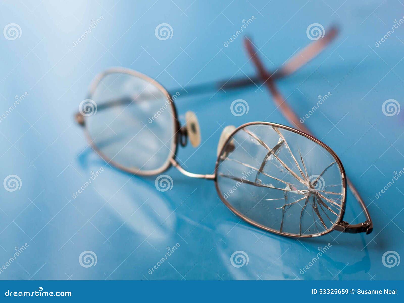 eyeglasses with cracked lens on shiny blue background