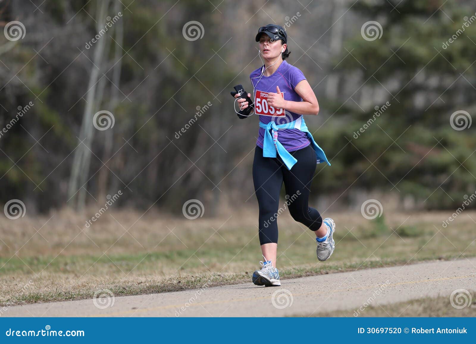 Żeński Maratoński biegacz. Kobieta biega przyrodniego maraton w wiośnie 2013 wzdłuż brukującego śladu przez parka w Edmonton, Alberta, Kanada, podnosić pieniądze dla olimpiad specjalnych.