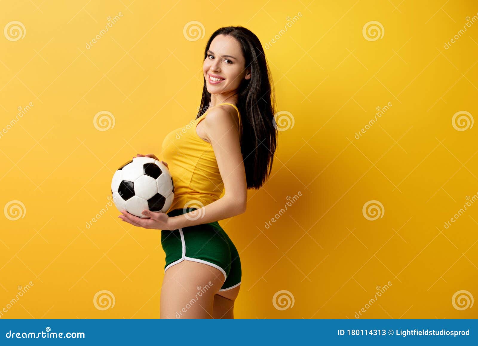 Foto Homem em calções amarelos segurando bola de futebol amarela e
