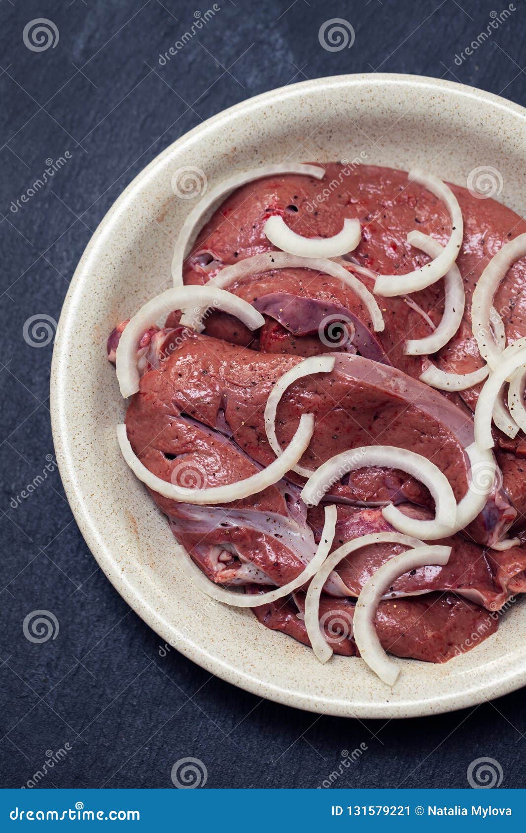 Fígado de frango frito com cebola e salsa em um prato fundo escuro