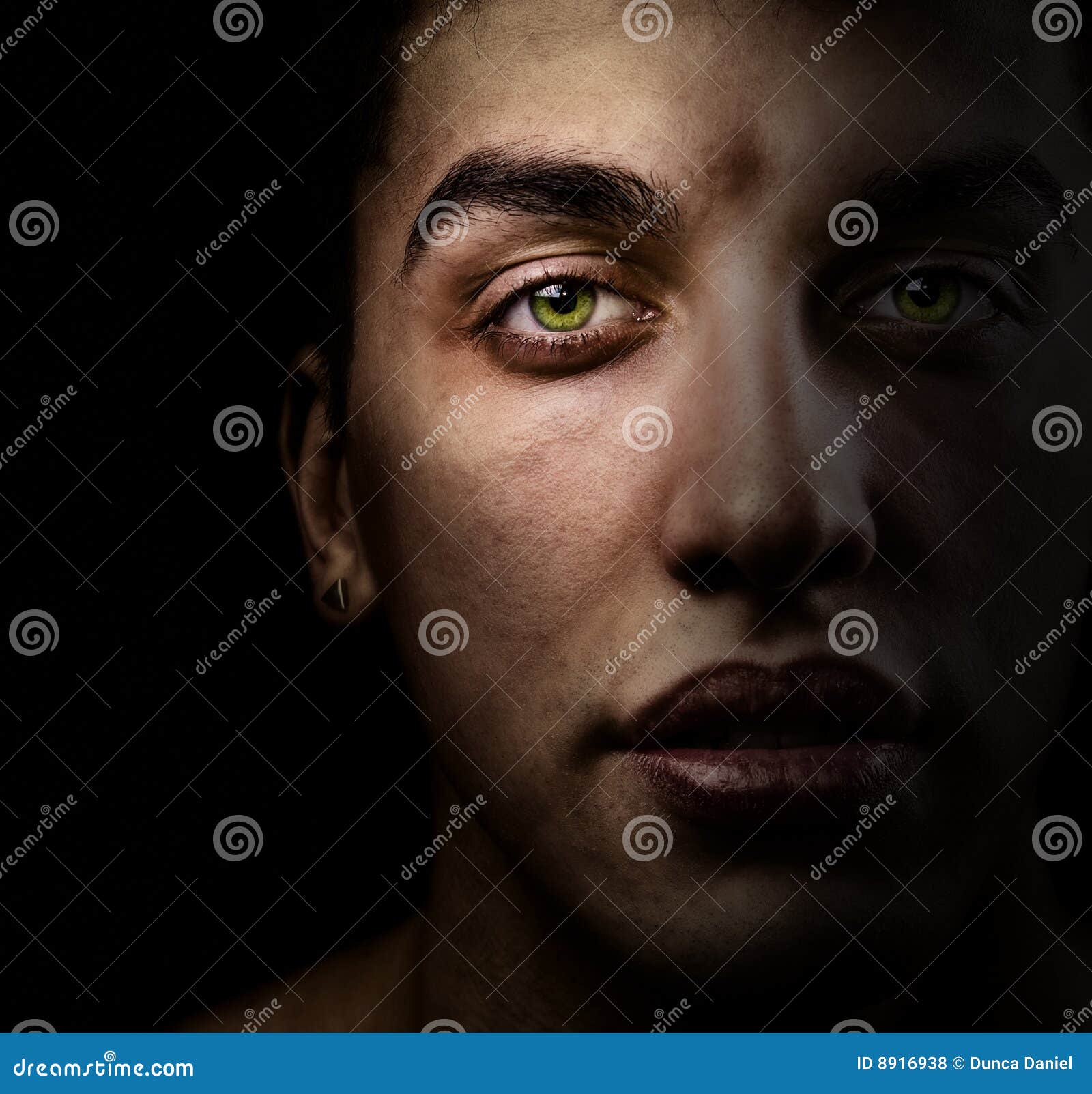 Face of Man in the Dark with Beautiful Green Eyes Stock Photo Image
