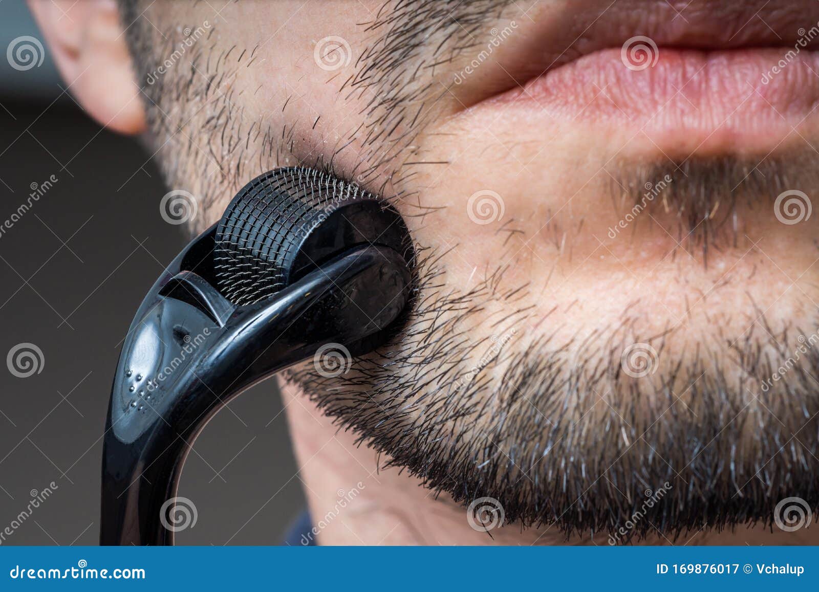 facial hair care concept. young man is using derma roller  on beard.