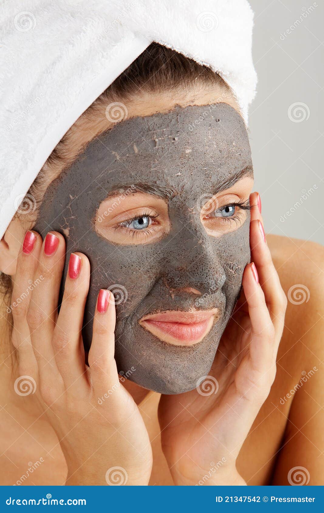 Beautiful woman with purifying facial mask keeping her palms by her face