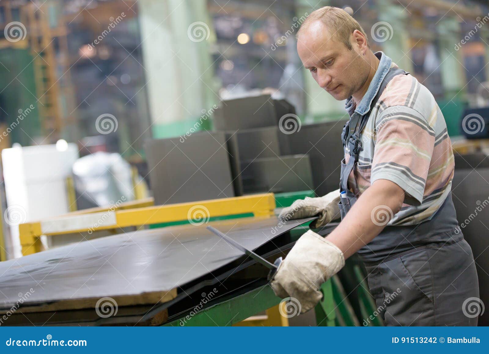 Factory Worker Removing Metal Burrs from Steel Sheet Stock Photo