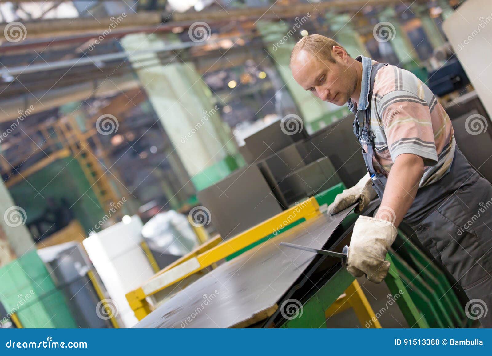 Factory Worker Removing Metal Burrs from Steel Sheet Stock Photo
