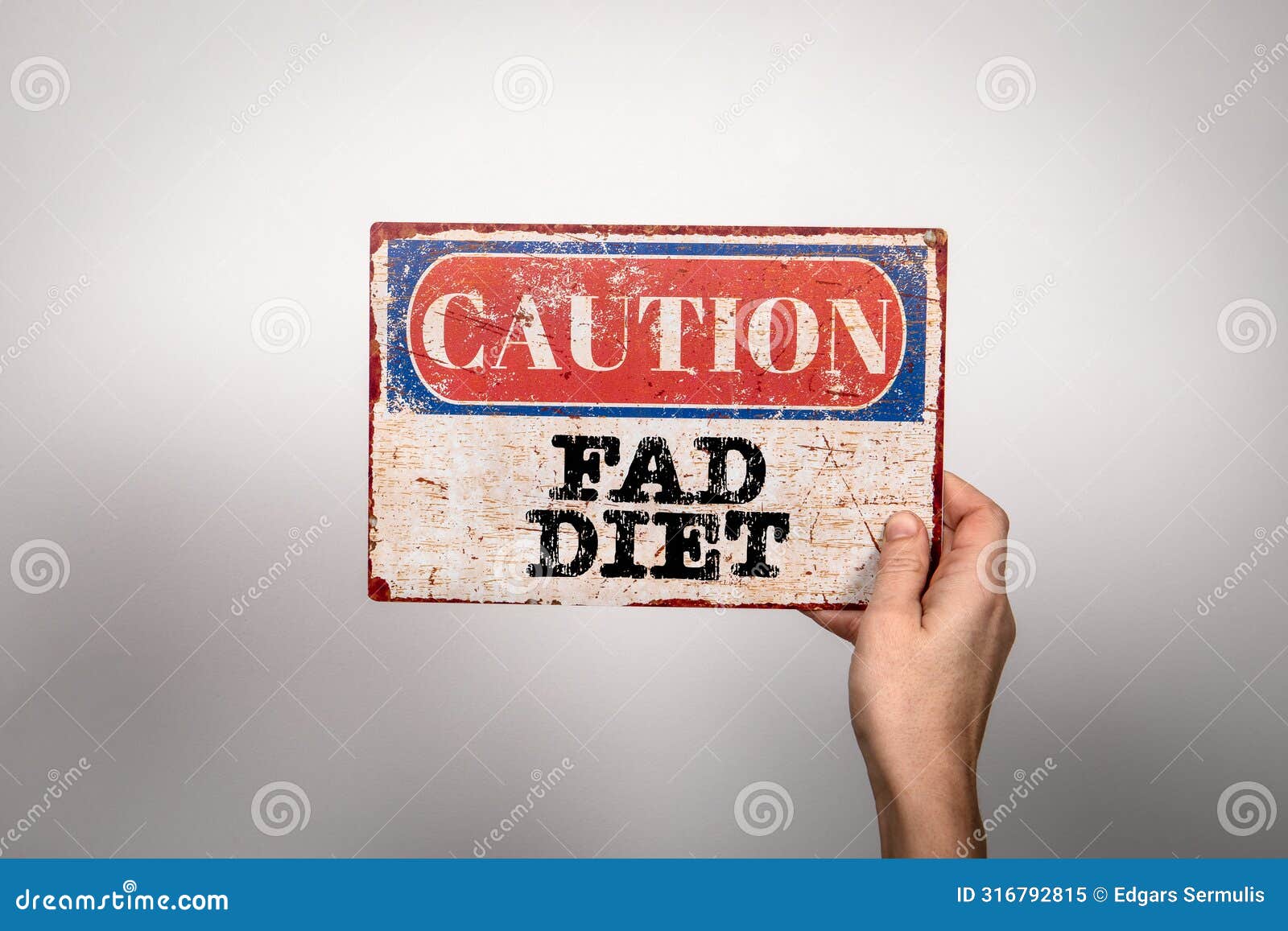 fad diet. metal warning sign in a woman's hand on a white background