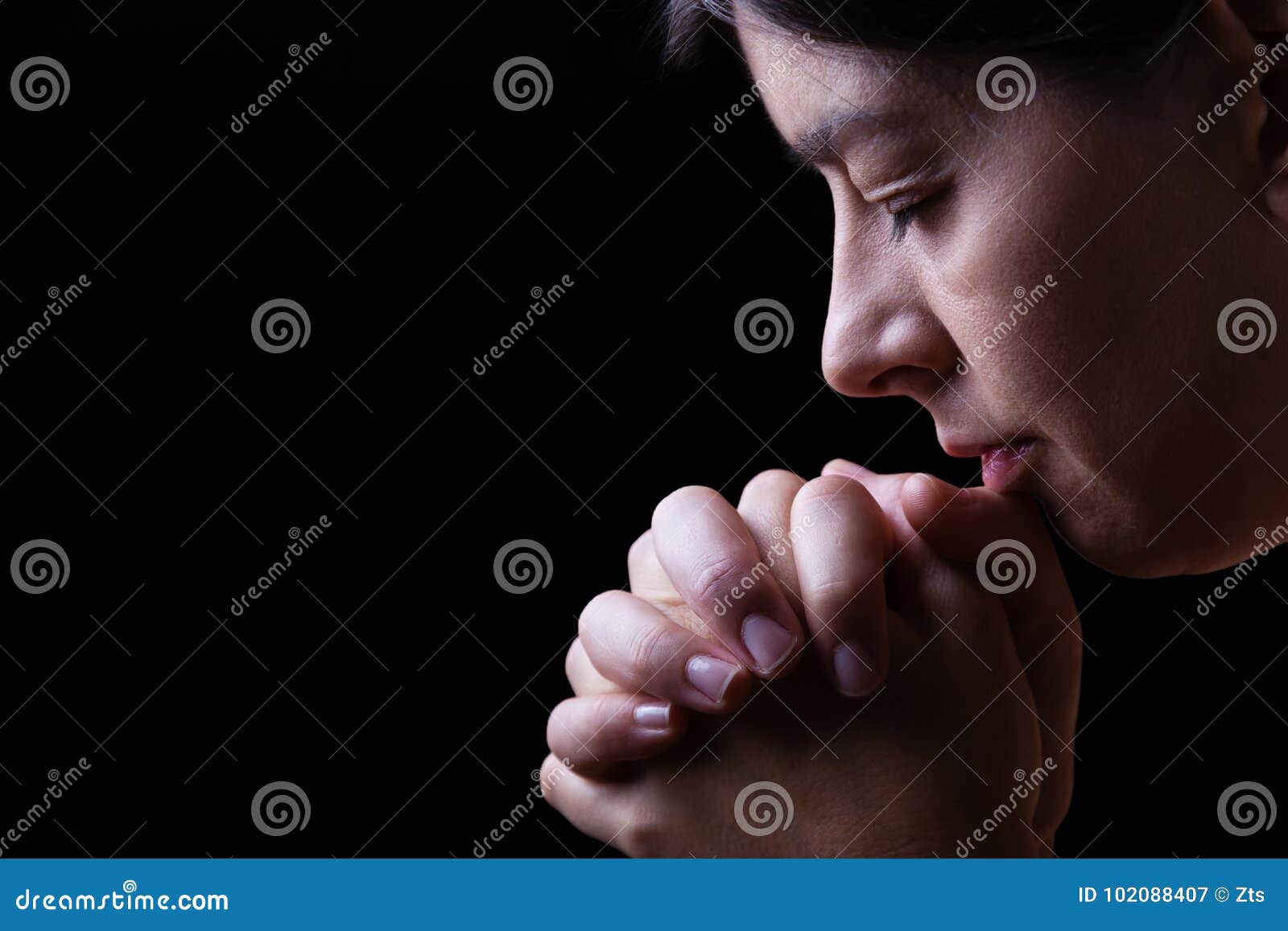 faithful woman praying, hands folded in worship to god