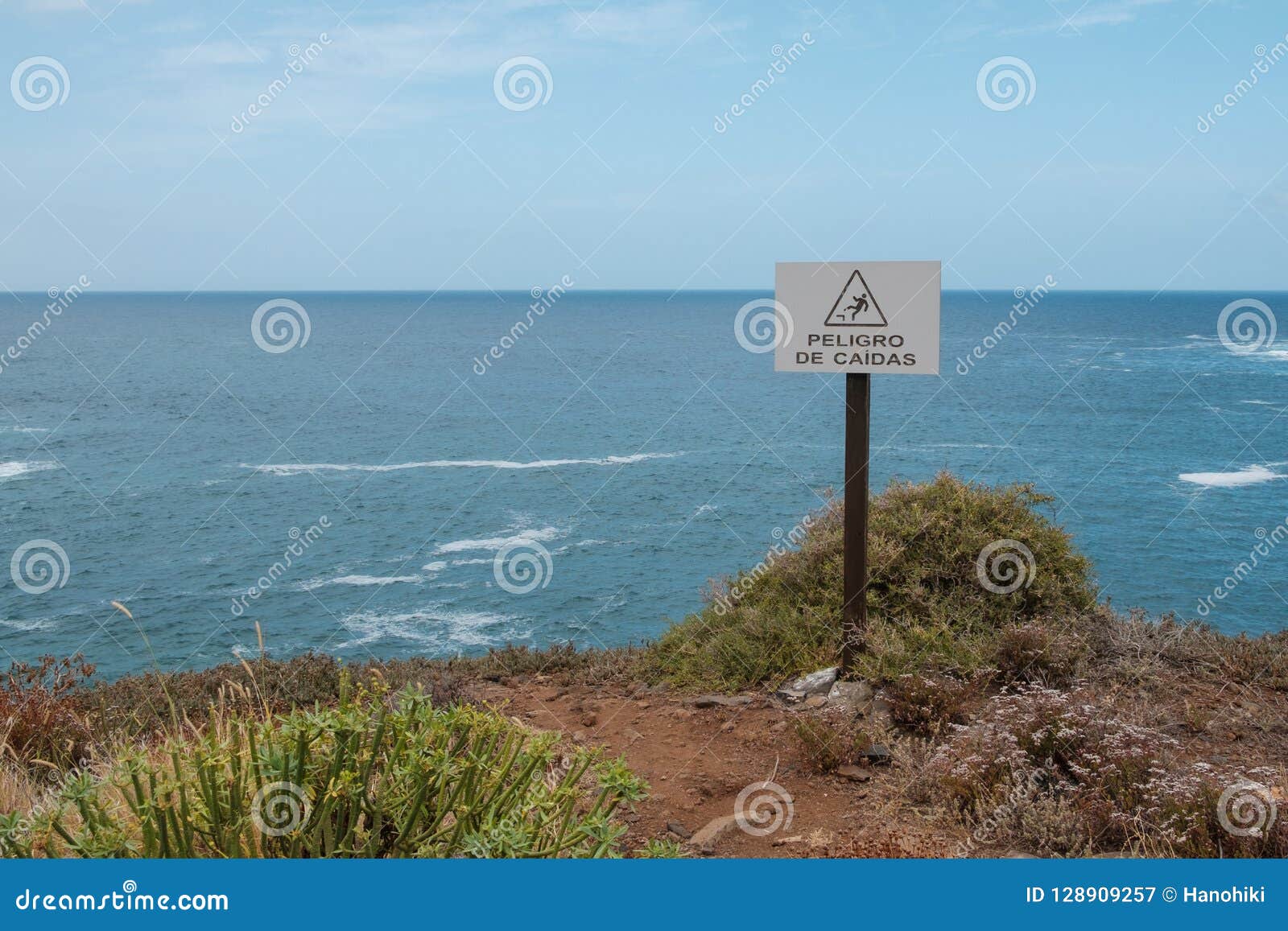 fall hazard spanish: peligro de caidas warning sign with ocean