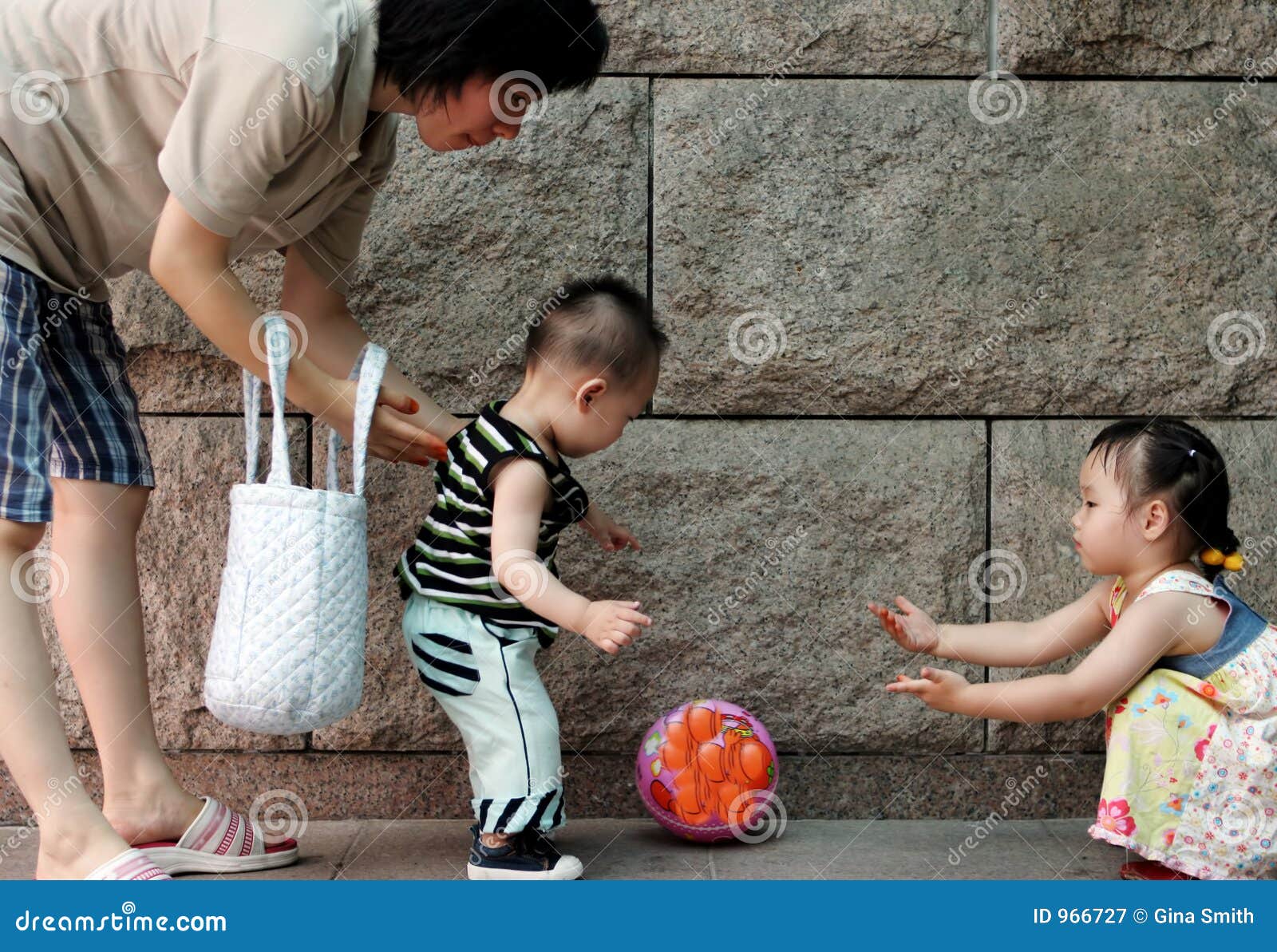 Famiglia che gioca con una sfera. La madre coreana gioca la sfera con i suoi bambini