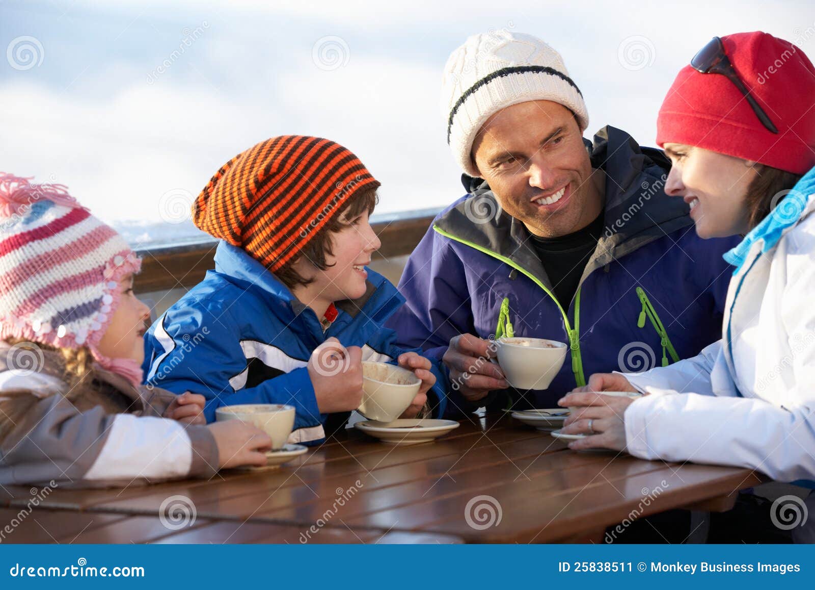 Famiglia che gode della bevanda calda in caffè alla stazione sciistica in vacanza in montagne