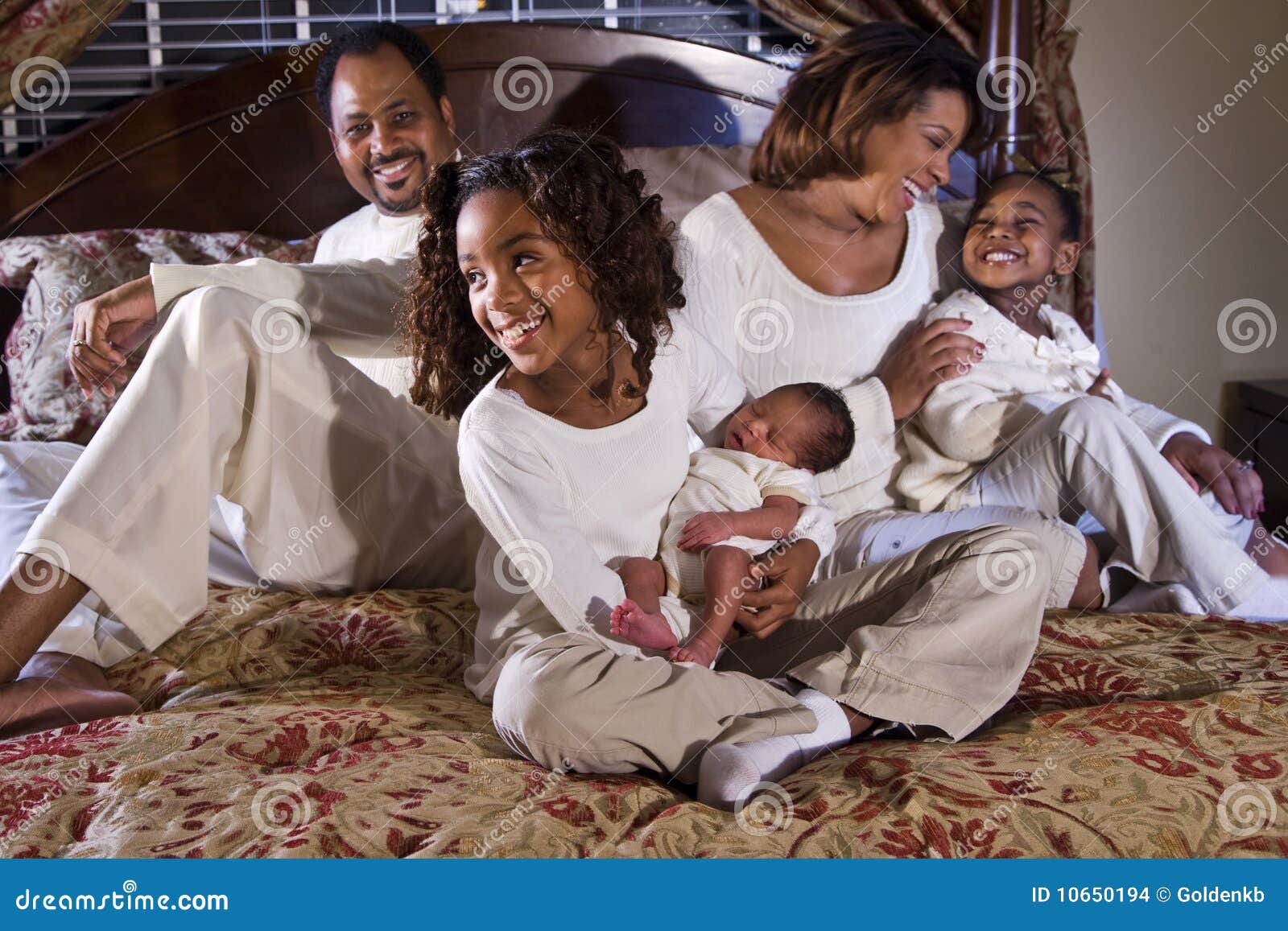 Familia con recién nacido. Familia feliz del afroamericano con la hermana grande que detiene al hermano recién nacido