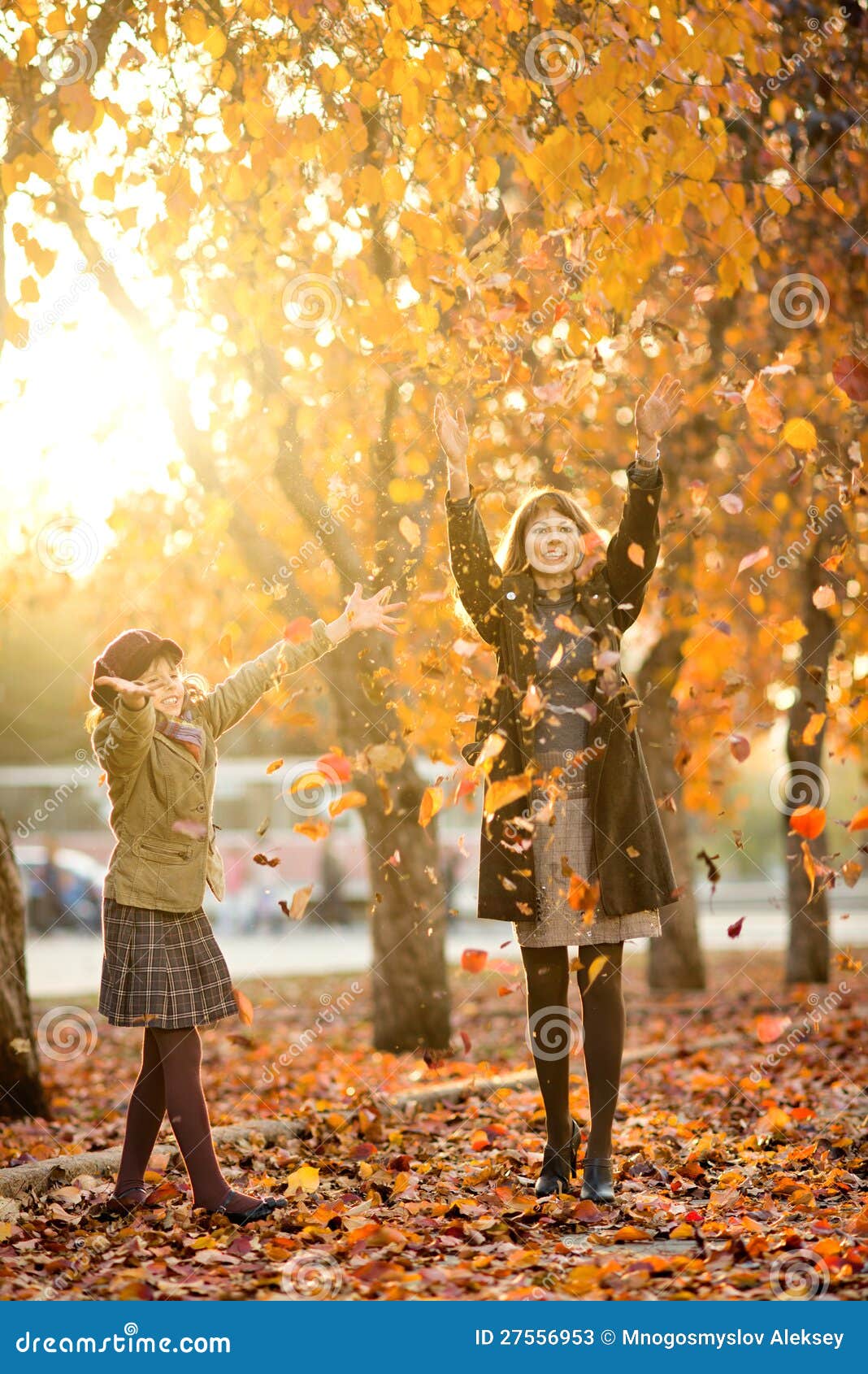 Familia feliz. La foto vertical, niña hermosa feliz con el mather lanza para arriba leafage otoñal, en parque. Foco en niña.