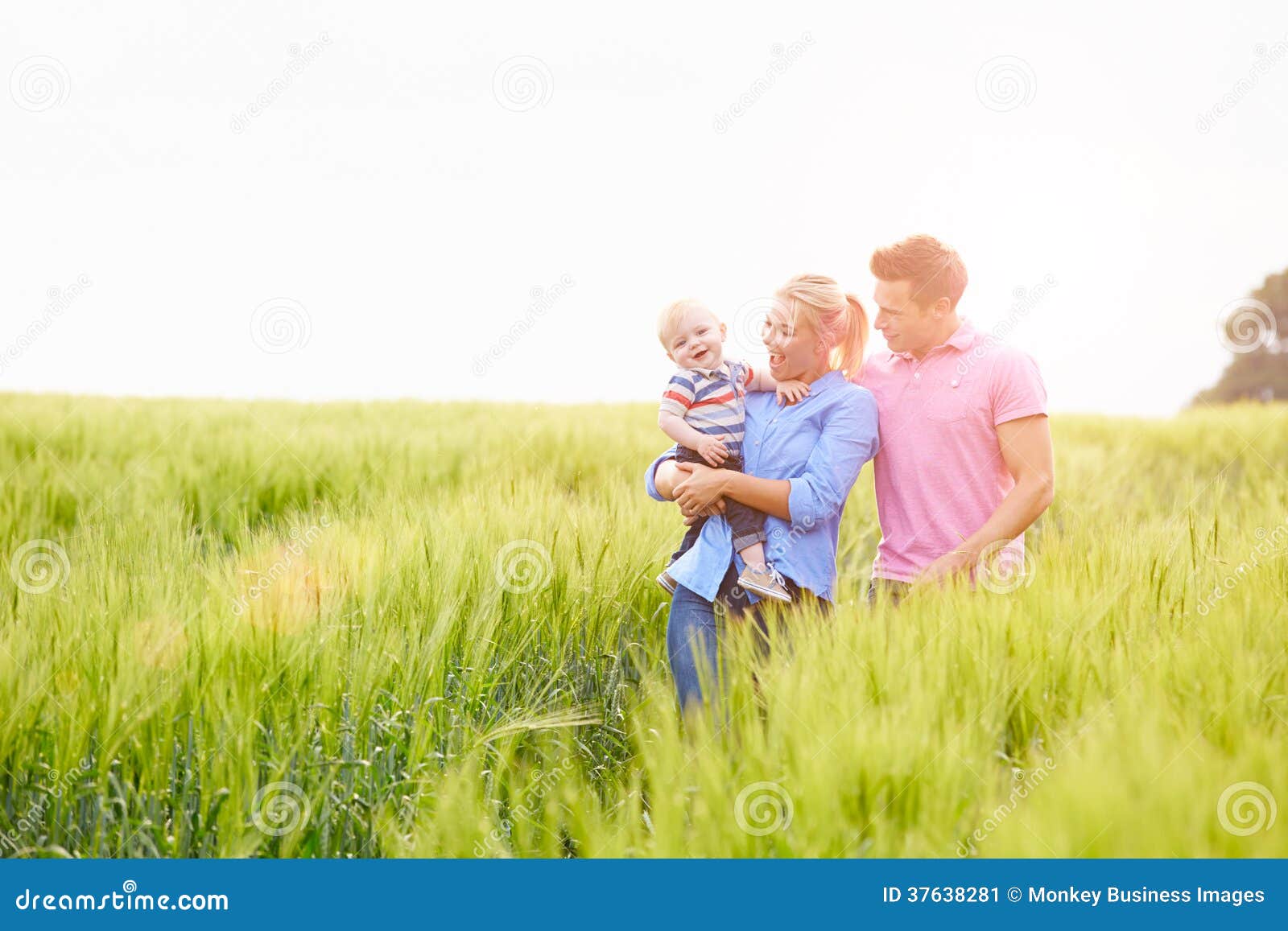 Familia que camina en el campo que lleva al hijo joven del bebé. Familia feliz que camina en el campo que lleva al hijo joven del bebé en el campo