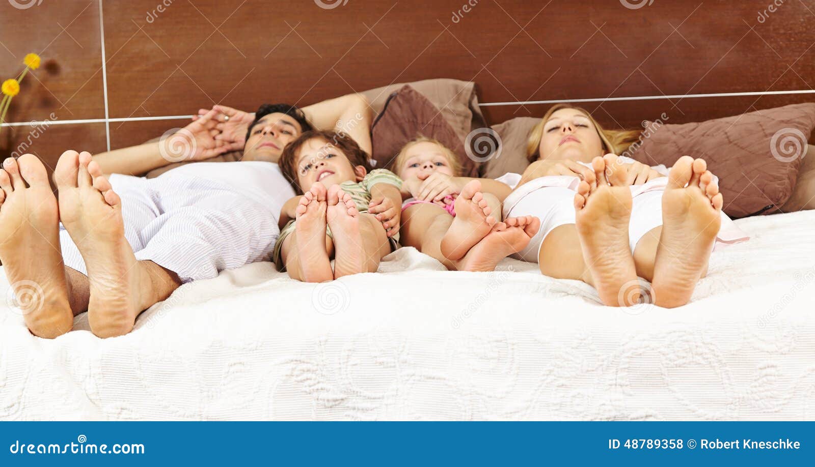 Familia que pone en cama con los pies adelante. Familia con dos niños que ponen en cama con sus pies adelante