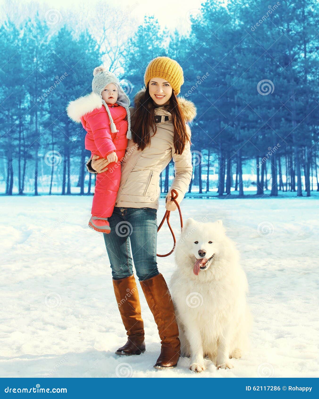 Familie in de winterpark, gelukkig moeder en kind die met witte Samoyed-hond lopen