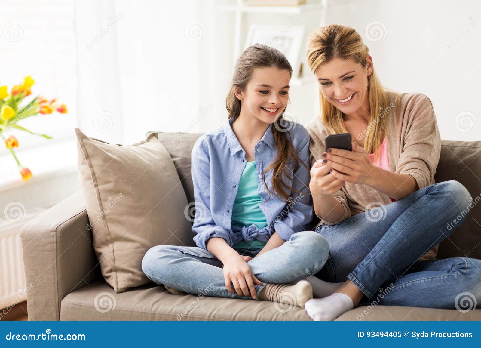 Famille heureuse avec le smartphone à la maison. Les gens, la famille et le concept de technologie - fille et mère heureuses avec le smartphone à la maison