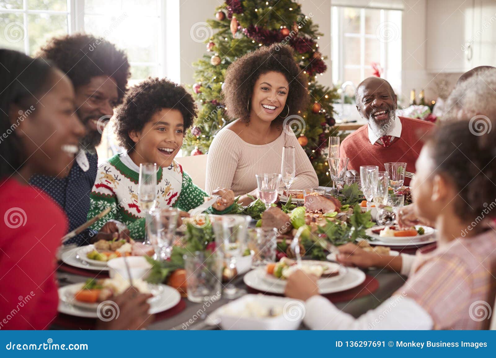 Famille multi heureuse de métis de génération se reposant à leur table de dîner de Noël mangeant et parlant, foyer sélectif