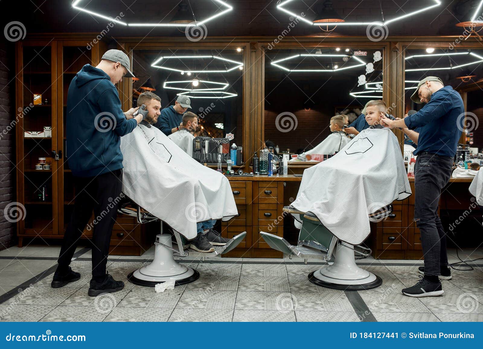 Family at Barbershop. Young Father and His Little Happy Son Sitting