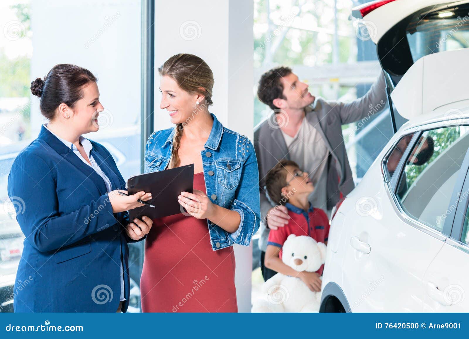 family buying new car in auto dealer showroom