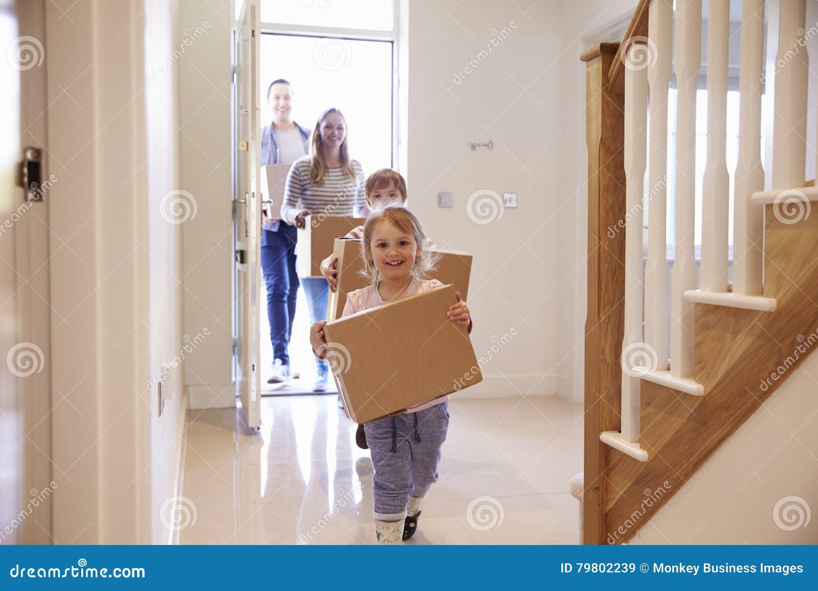 family carrying boxes into new home on moving day