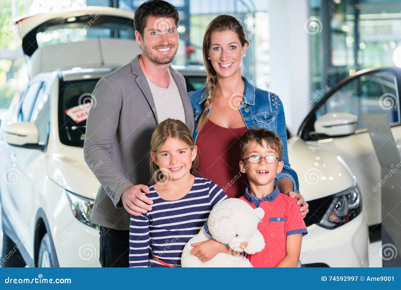 family with children buying new car at auto dealership