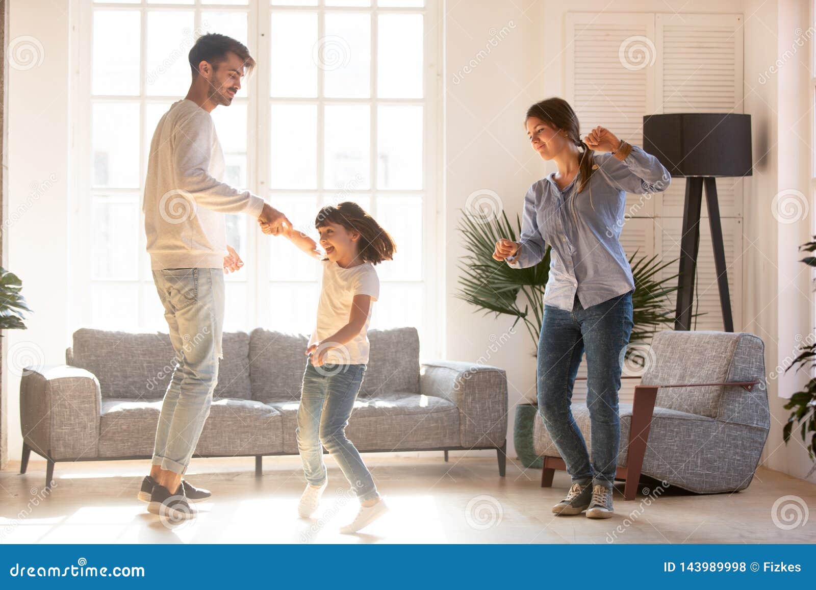 Family dancing in living room spending time on weekend together