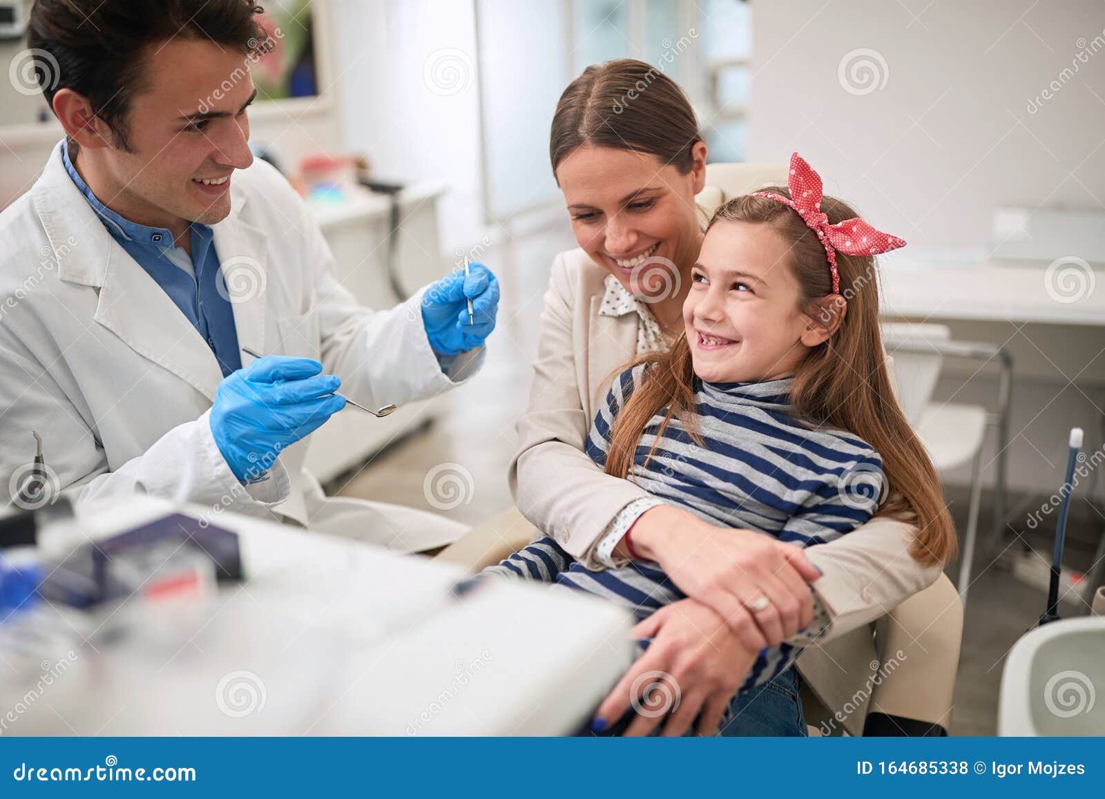 family in dentistÃ¢â¬â¢s office.dentist examining his girl patient in dentistÃ¢â¬â¢s clinic