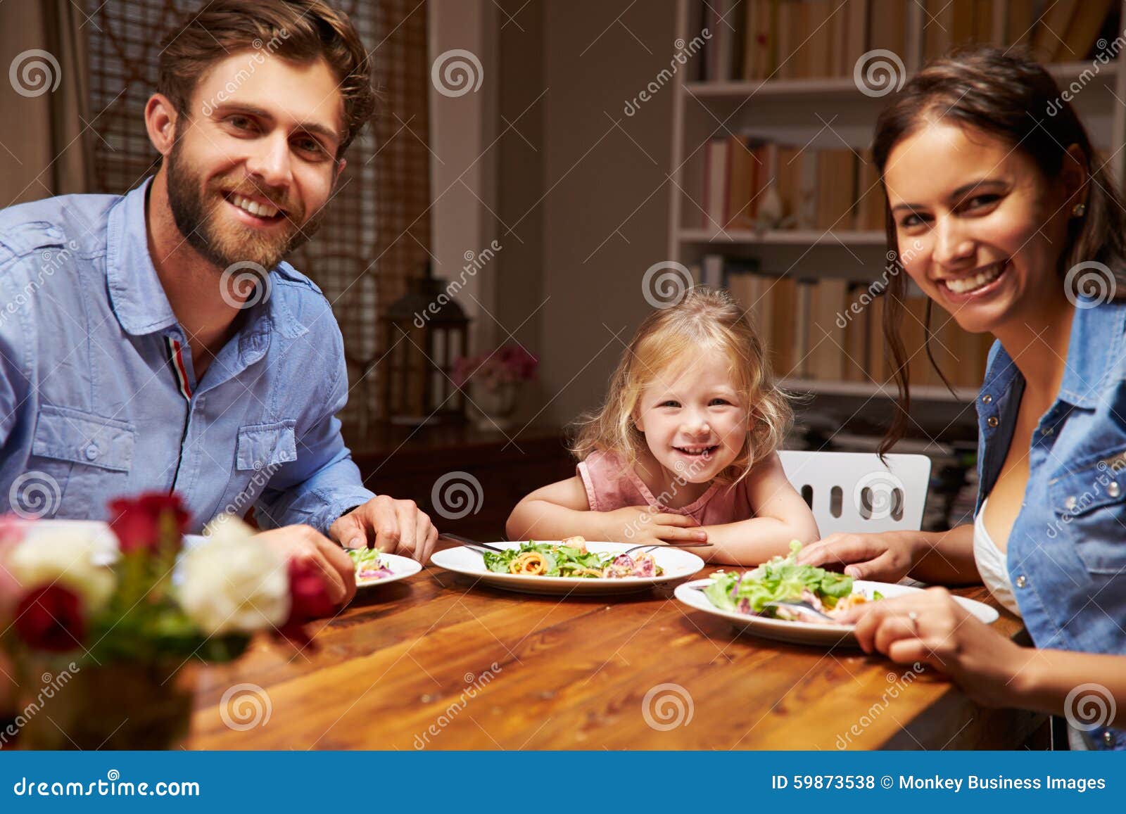 Family Eating Dinner at a Dining Table, Looking at Camera Stock Photo