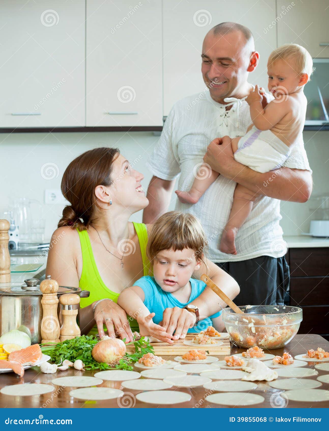 Family of Four Together in the Kitchen Prepares Food Stock Photo