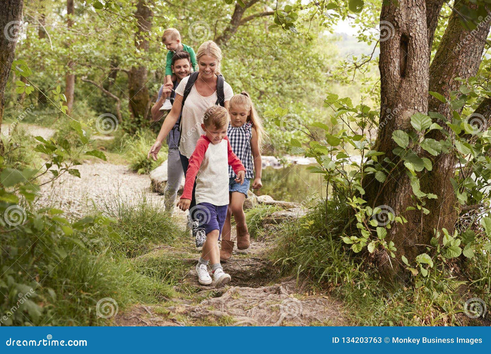 family hiking along path by river in uk lake district