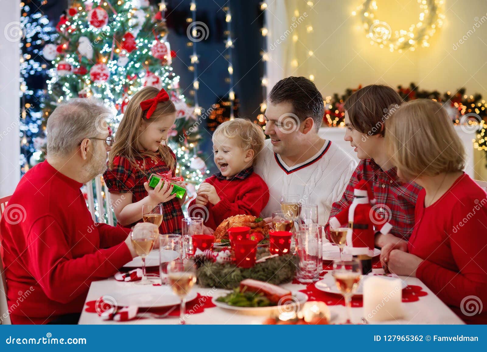 family with kids having christmas dinner at tree