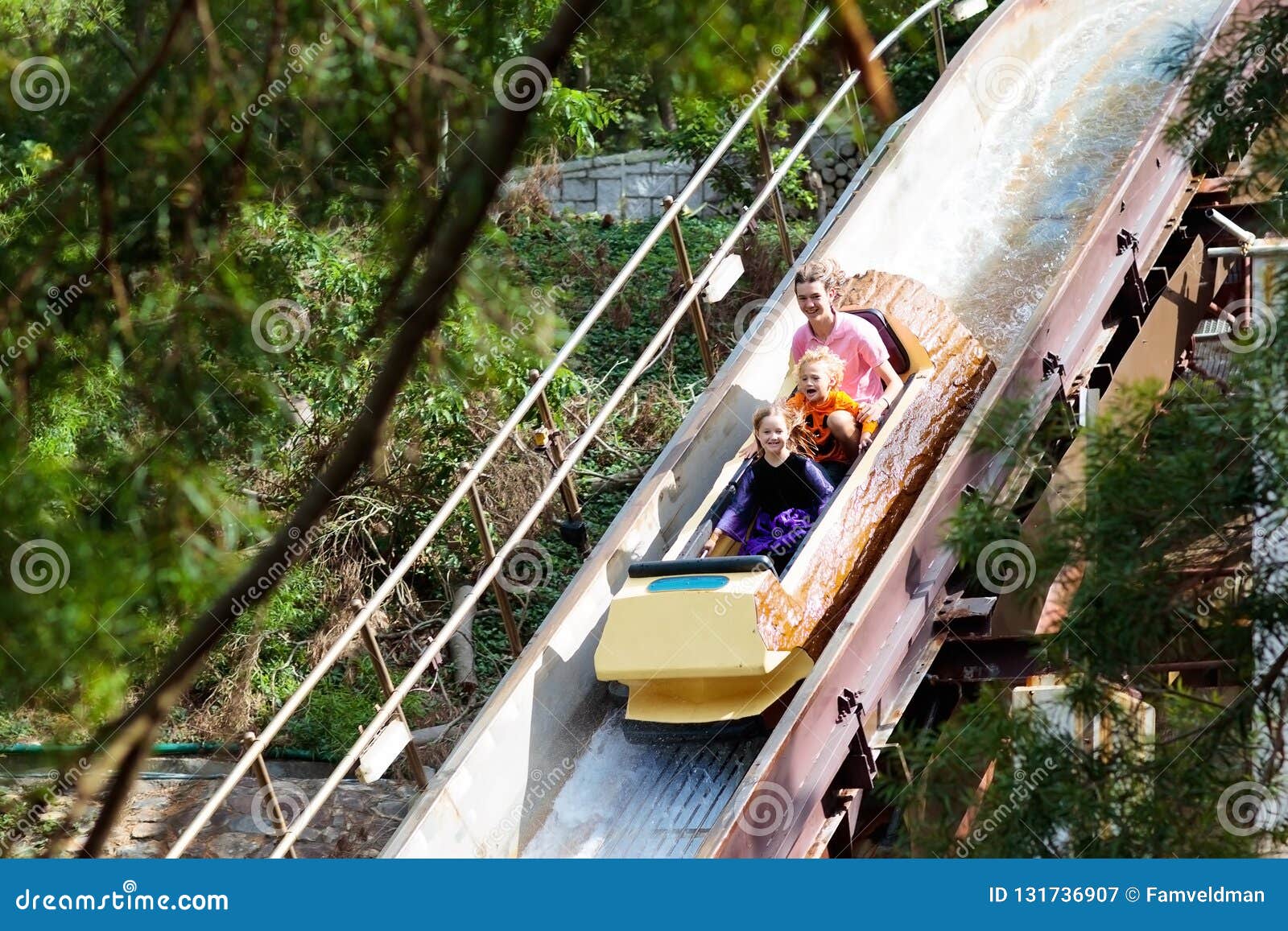 family with kids on roller coaster in amusement theme park. children riding high speed water slide attraction in entertainment fun