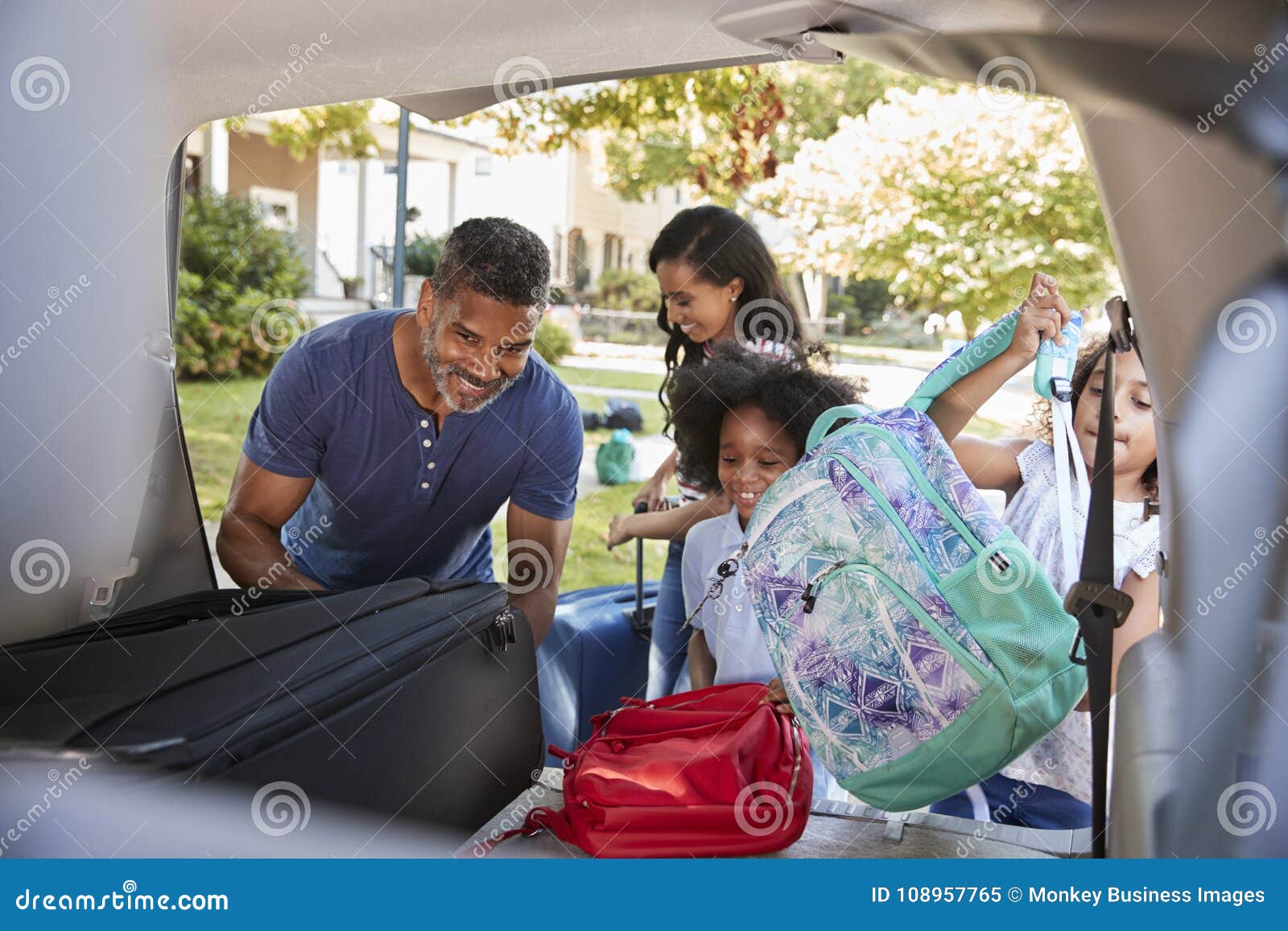 family leaving for vacation loading luggage into car