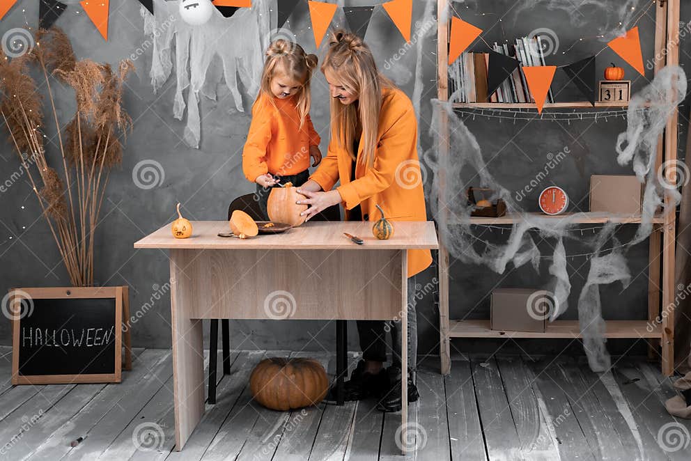family-mom-and-daughter-prepare-pumpkin-for-halloween-at-home-in-a