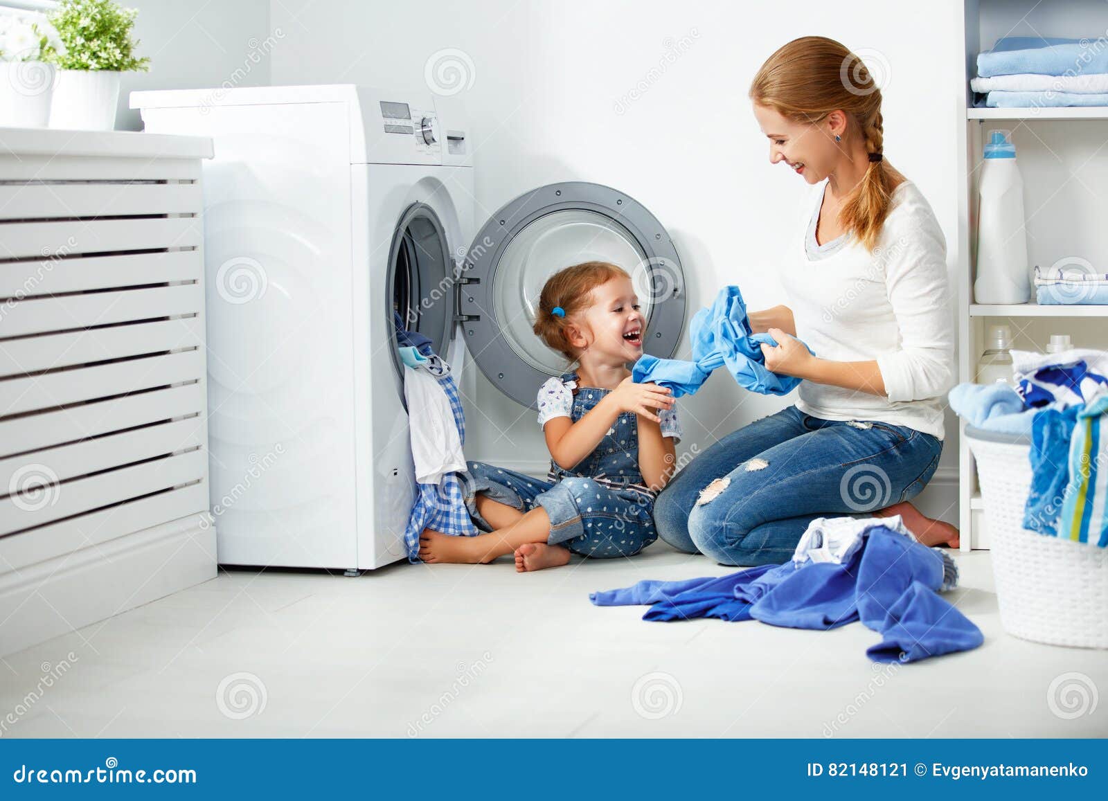 family mother and child girl little helper in laundry room near washing machine