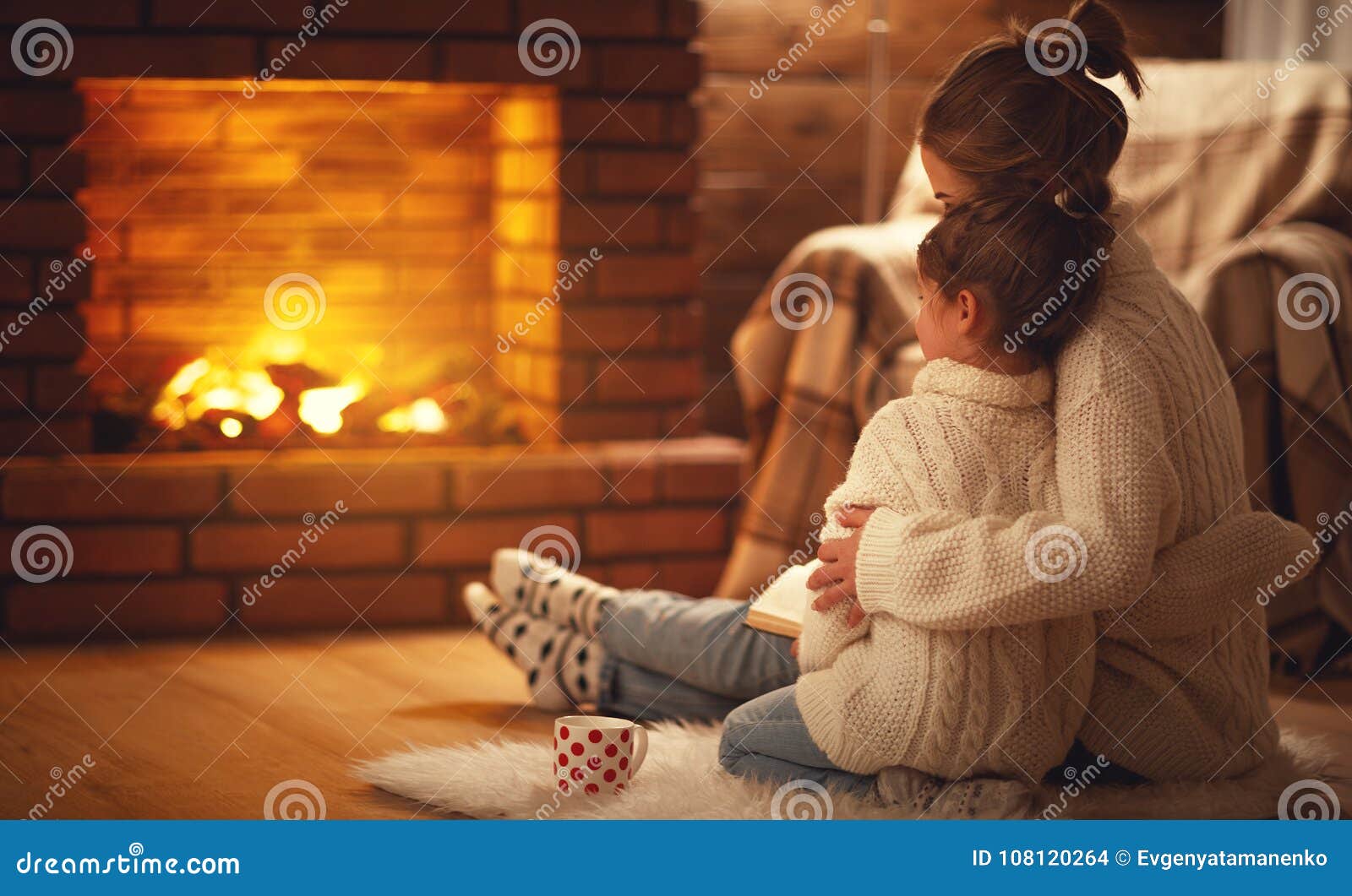 family mother and child hugs and warm on winter evening by fireplace.