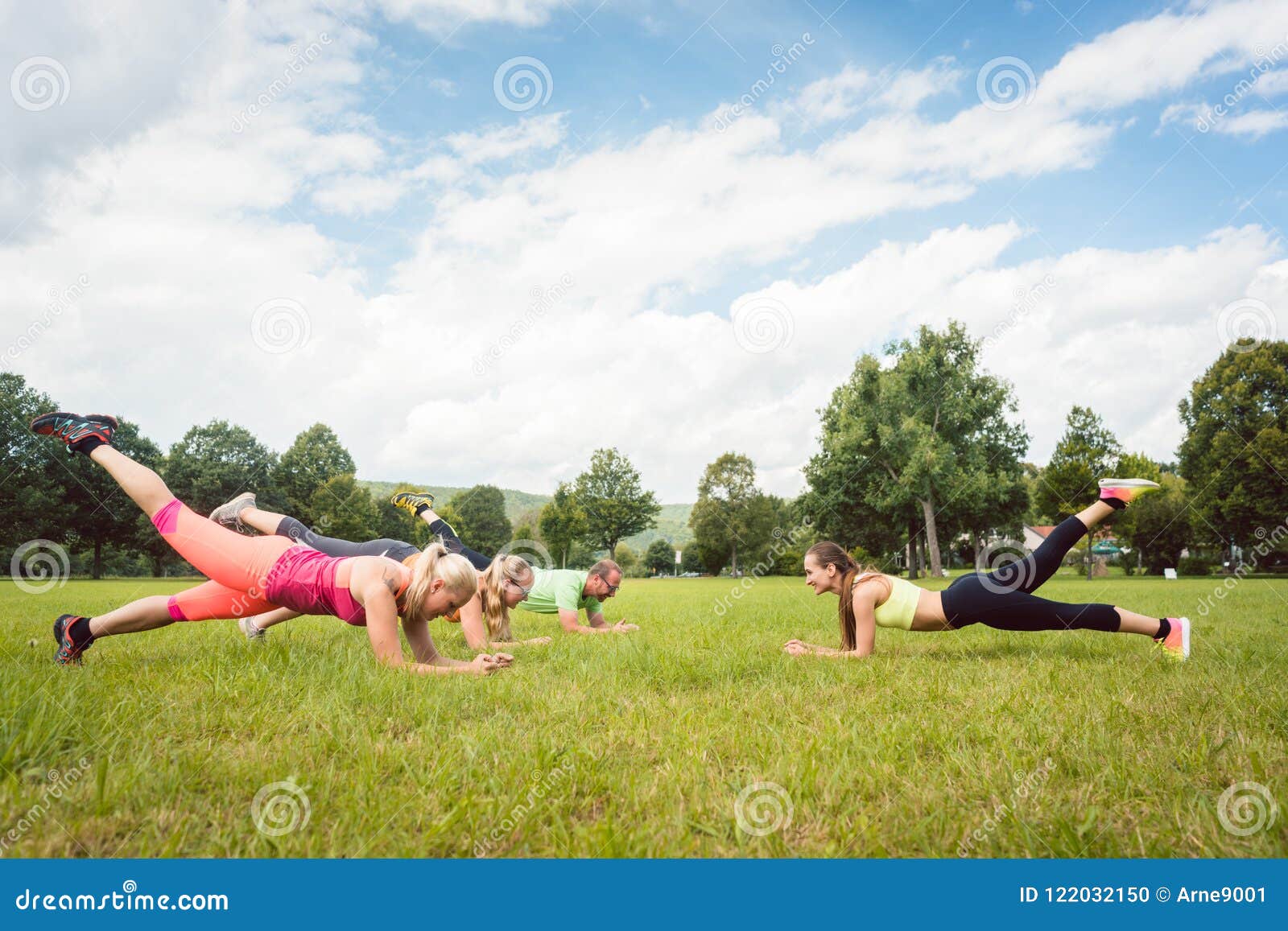 family planking outdoors in meadow with fitness teacher